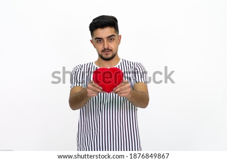 Young man wearing a striped T-shirt. He is holding a heart-shaped box. Isolated White background.