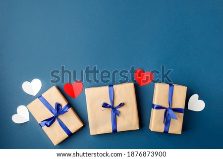 Paper craft gift boxes with bow on blue background with hearts, copy space. Greeting card concept. Saint Valentine, romance, Dad day, wedding, new year, birthday, wedding, mother day