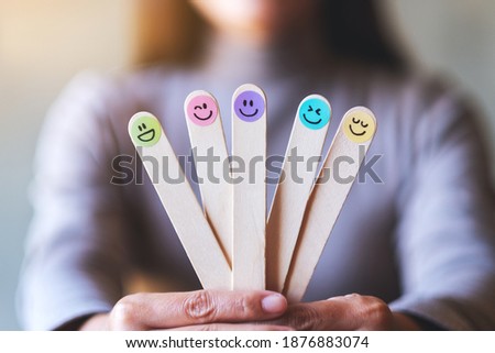 A woman holding colorful hand draw happy emotion faces on wooden stick