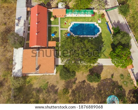 Aerial shot of green lawn in country house and garden with pool in the backyard.