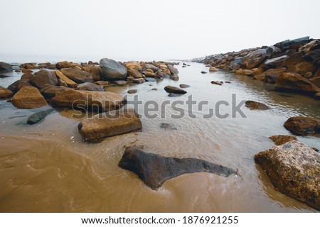 Quiet water and seashore rocks at an overcast day