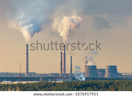 Smoke from chimneys at the plant in the rays of the sunset.