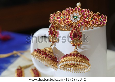 close up of head clip and a pair of temple jewelry arranged on a white porcelain cup Royalty-Free Stock Photo #1876975342