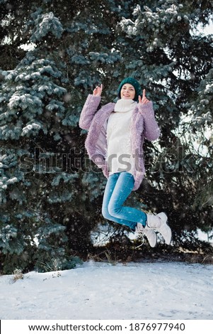 Portrait of young cozy woman in warm clothes in sunny winter day. snow blowing winter fun. Joyful Winter and Christmas time concept