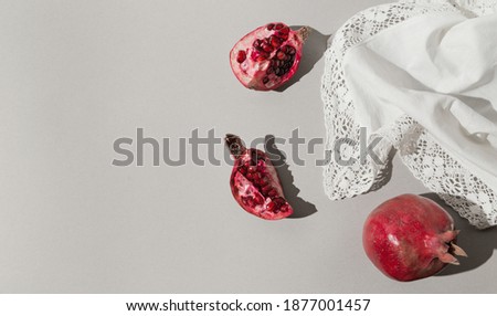 Fresh pomegranates in light on white fabric background. Beautiful backdrop for cards, blogs, posters and web design. selective focus