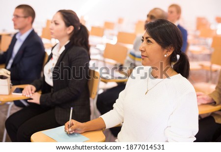 Portrait of focused Latina attending business conference, listening with interest to speaker