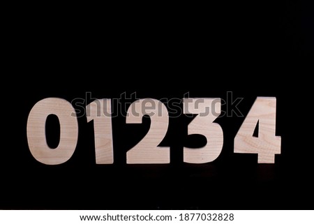 Large wooden numbers 0 1 2 3 4. Hardwood characters on a black background