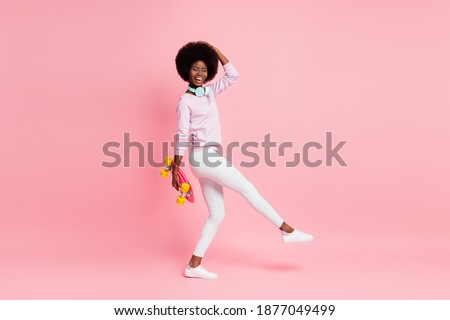 Full length body size view of pretty dreamy ecstatic cheery skinny wavy-haired girl carrying skate dancing isolated over pink color background