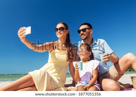 family, leisure and people concept - father, mother and little daughter taking selfie with smartphone on summer beach