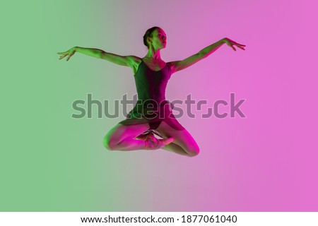 Inspired. Young and graceful ballet dancer isolated on gradient pink-green studio background in neon. Art, motion, action, flexibility, inspiration concept. Flexible ballerina, weightless jumps.
