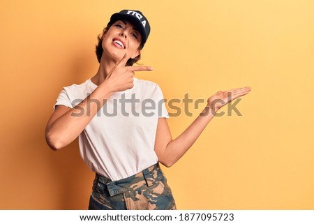Young beautiful woman wearing usa cap amazed and smiling to the camera while presenting with hand and pointing with finger. 
