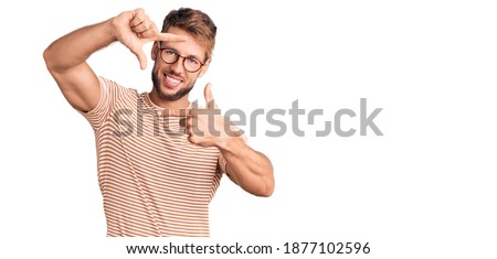 Young caucasian man wearing casual clothes and glasses smiling making frame with hands and fingers with happy face. creativity and photography concept. 