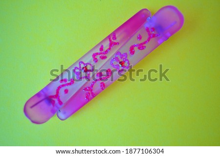 Two pink hair clips with flower pattern on yellow background