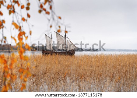 Wooden old ship in vintage style with all sails set in misty lake. Moody background.