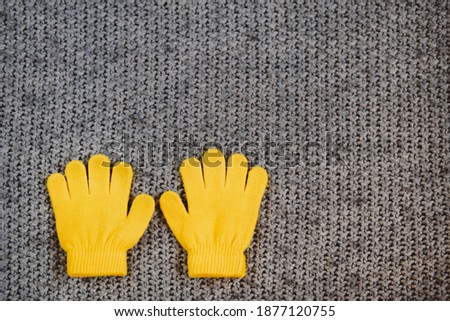 Yellow mittens on gray background.