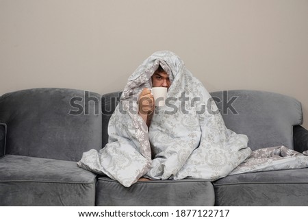 Sick day at home. Handsome Man has fever and common cold. Cough. middle aged guy Caught Cold Or Flu Illness. Portrait Of Unhealthy man Feeling Pain In Throat. morning scene. male wrapped in blanket Royalty-Free Stock Photo #1877122717