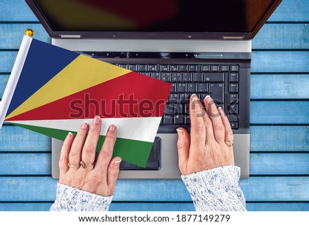  woman hands and flag of Seychelles on computer, laptop keyboard 