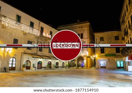 A barrier with a prohibition sign and capture "LOCKDOWN" on a background of night Christmas city