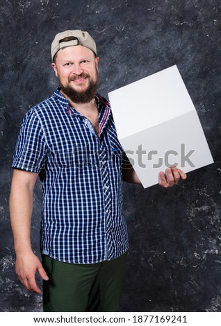Joyful bearded man in shirt with blanc cube object for your logo studio portrait