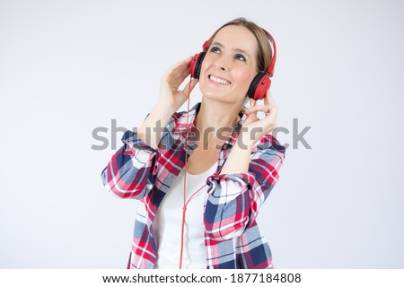 Pretty young woman listens and enjoys the music in headphones over white background.