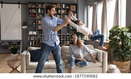 Wide banner view of loving young Caucasian father have fun play with excited small daughter relax at home. Caring parents feel playful engaged in funny activity with little girl child in living room.