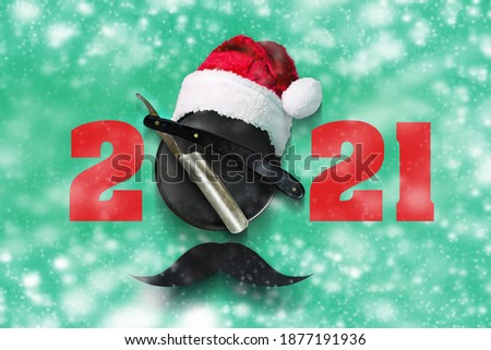 2021. Razor, Santa Claus hat, on a green background. Snow effect. Happy New Year for the Barbershop. Festive background.
