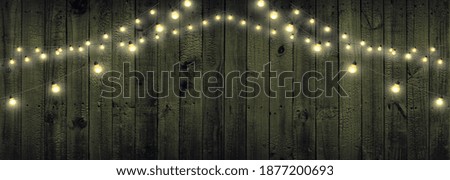 Christmas lights isolated on brown wooden background. Glow garland. Copy space for a greetings.
