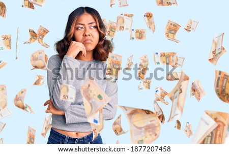 Young beautiful mixed race woman wearing casual clothes serious face thinking about question with hand on chin, thoughtful about confusing idea