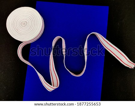 White red cotton ribbon with curl. Used for clothing,packing,wrapping. Isolated on blue and black background