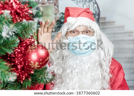 Santa Claus in blue facemask and eyeglasses waving greeting gesture with hand. Christmas and new year concept.