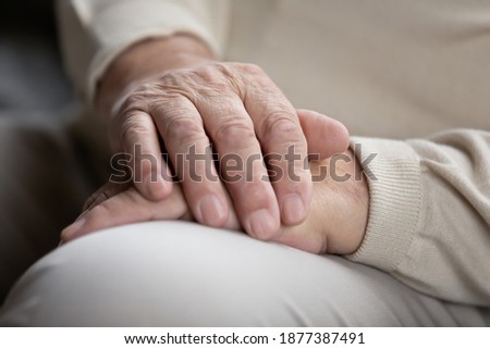 Close up of elderly male sitting alone keeping wrinkled work-weary hands folded on knees. Retired old man think ponder of loneliness need attention care. Senior person waiting for doctor appointment Royalty-Free Stock Photo #1877387491