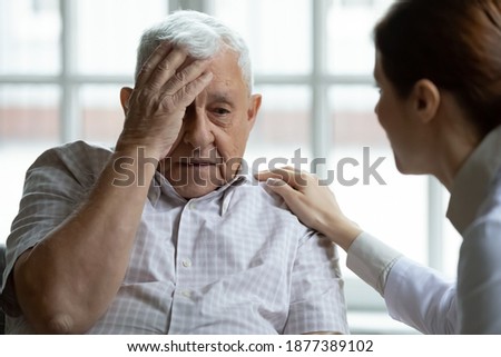 Attentive young lady physician interview senior patient on meeting listen to complaints make diagnosis. Stressed sad elderly man visit trusted capable doctor feel headache dizzy problems with memory Royalty-Free Stock Photo #1877389102