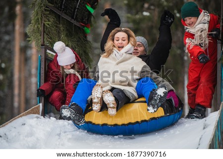 Winter family entertainment - tubing downhill, family having fun.
