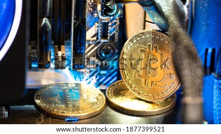 Bitcoin golden coins on a motherboard with neon light. 