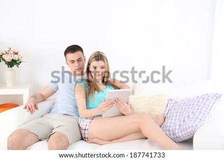Loving couple  relaxing with tablet, on home interior background