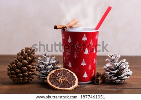 Red cup with hot drink and New Year's decor on a brown wooden background.