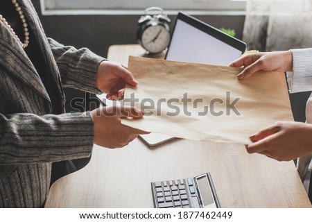 Hand of business woman giving envelope to colleague in modern office. Promotion, HR concept, unemployment concept, searching for job, envelope with Job offer message Royalty-Free Stock Photo #1877462449