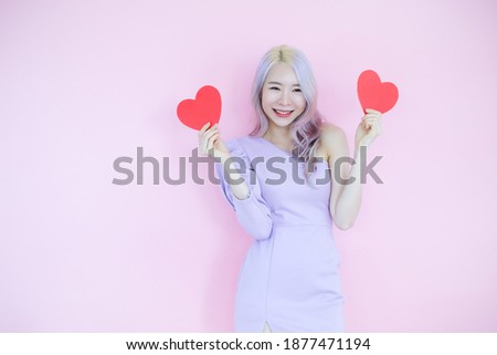 Portrait beautiful asian woman on pink background, happy valentine day in love concept, model holding red heart sign in hand