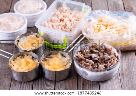 Frozen food. French dish julienne. Mushroom, chicken and cheese gratin in bowls on wooden table