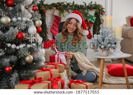 Young woman with present near Christmas tree at home