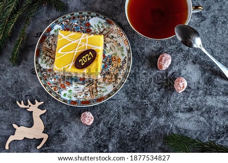 New Year's photo of a cake with tea, dried kumquat on a table with fir branches and toys, postcard
