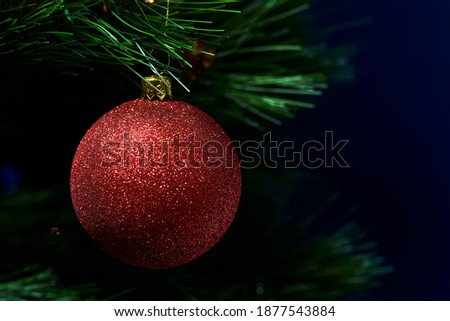 Closeup of a red christmas ball, hanging from a fir tree