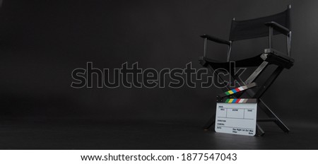 Director chair and Clapper board or Clapperboard or movie slate use in video production or film and cinema industry. It's put on black blackground. Royalty-Free Stock Photo #1877547043