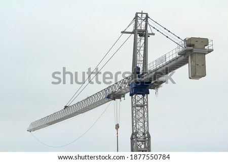 Tower crane works at a construction site against the blue cloud winter sky. Stock photo with empty space for text and design.