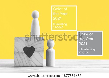 Small wooden figures of family members toned into colors of the year 2021 Ultimate Gray and Illuminating