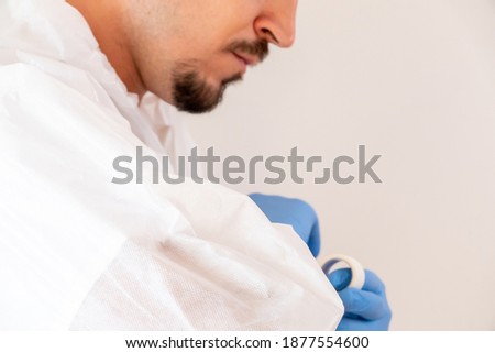 A doctor in mask putting on a PPE protective suit for coronavirus - concept of new normal