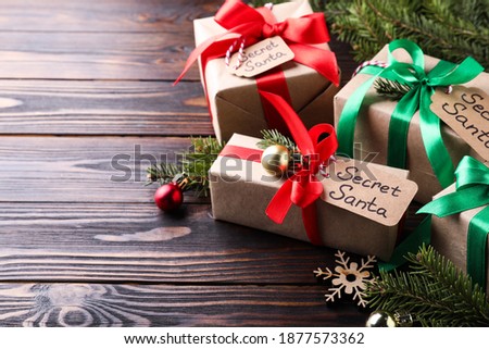 Presents from secret Santa and Christmas decor on wooden table, space for text
