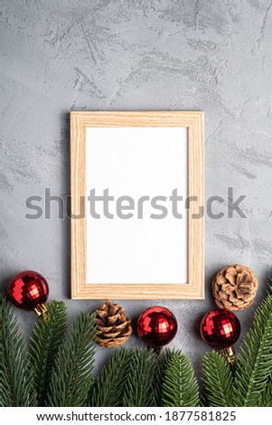 Christmas holidays composition with picture frame mockup. Red baubles and fir-tree branches.