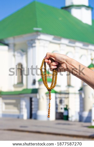 Muslim hands with muslim rosary. Against the background of the mosque.