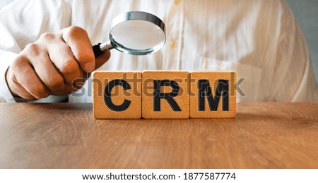 CRM inscription on the texture of wooden cubes. A business man holds a cube in his hand. An inscription on a financial, business or economic theme.